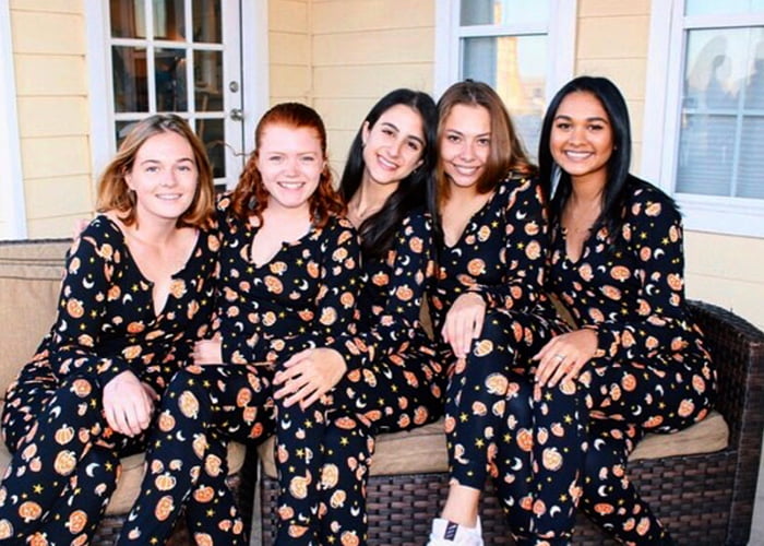Five women posing in similar patterned outfits.
