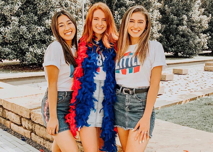 Three women, one wearing a red and blue feather boa.