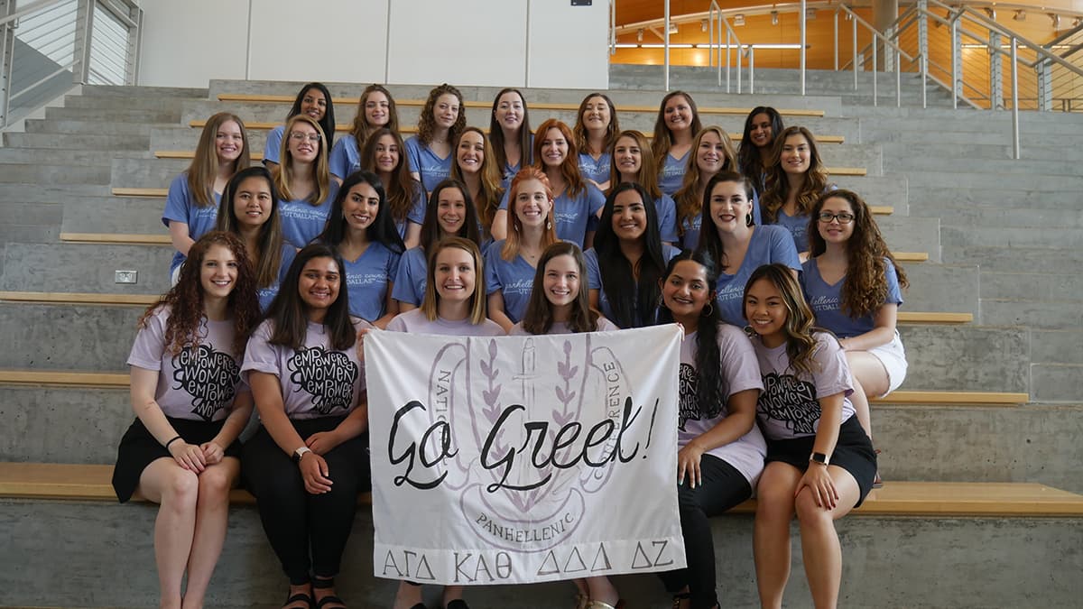 Group Photo of Sorority Member with a 'Go Greek' banner.