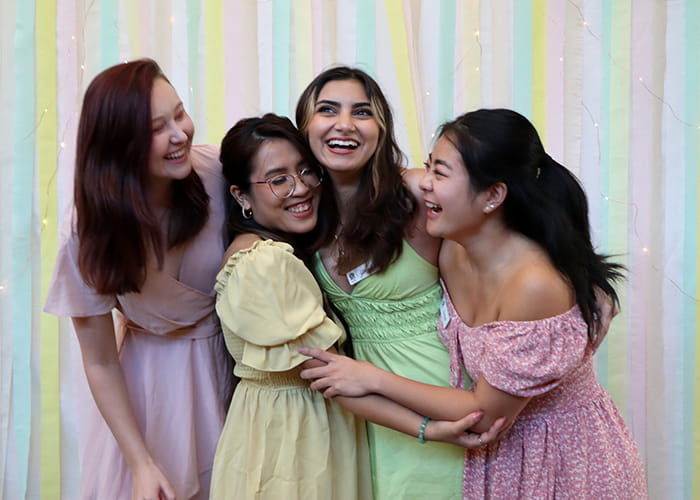 Group of women embracing in pastel colored dresses.