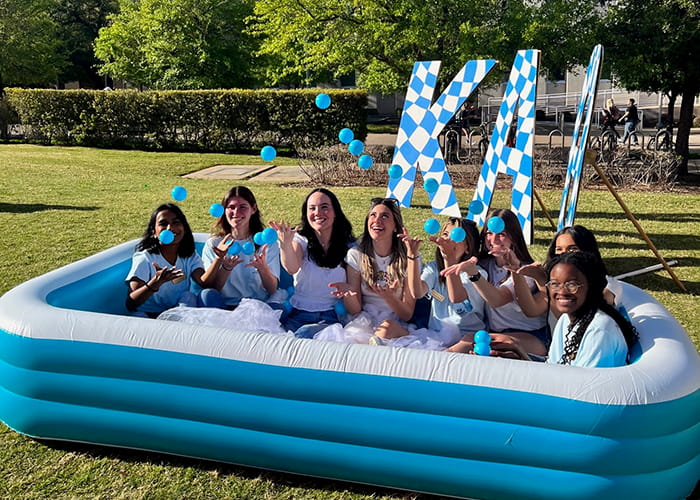 Women in an inflatable pool with the greek letters Kappa Alpha Theta in the background.